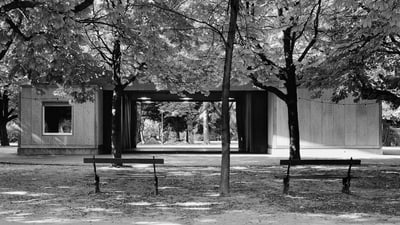 Zwei Bänke vor einem Pavillon im Park.