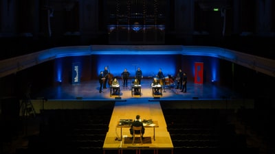 Orchesterprobe auf beleuchteter Bühne in einem Konzertsaal.