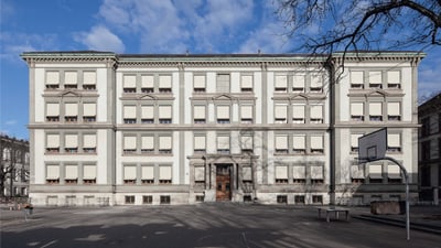 Altes Schulgebäude mit Basketballkorb im Vordergrund.