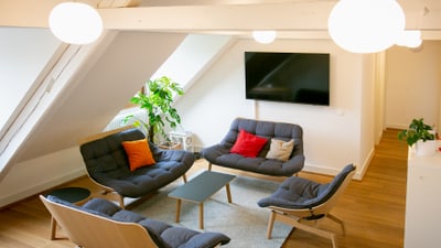 Modernes Wohnzimmer unter dem Dach mit grauen Sofas und grossen Fenstern.