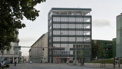 Strassenszene mit modernem Gebäude und Bäumen bei einer Kreuzung.