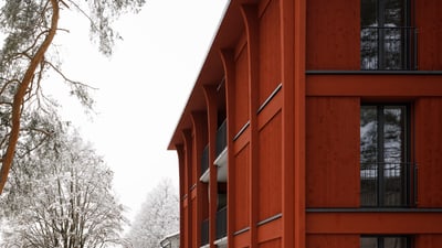 Modernes rotes Gebäude im Winter mit Schnee und Bäumen.