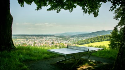 Tischtennisplatte auf einem Hügel mit Blick auf Stadt und Landschaft.