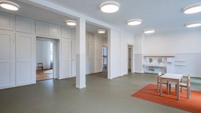 Moderner, leerer Raum mit Spieltisch und weissen Schränken.