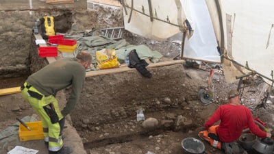 Archäologen arbeiten an einer Ausgrabungsstätte unter einem Zelt.