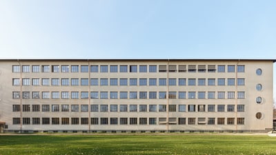 Moderne Bürogebäude-Fassade mit vielen Fenstern und einer Wiese im Vordergrund.