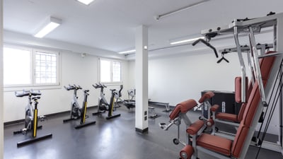 Fitnessraum mit Trainingsgeräten und Fahrrädern.