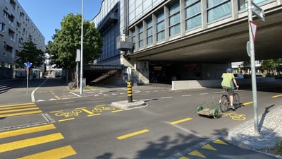 Radfahrer an einer Kreuzung in der Stadt mit Gebäuden und Fahrradwegmarkierungen.