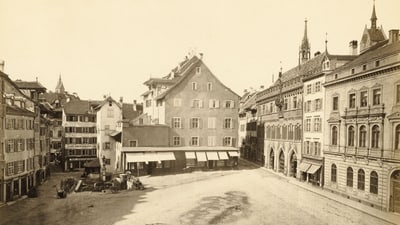 Historisches Foto eines leeren Platzes in einer Stadt, umgeben von Gebäuden.