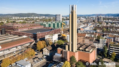 Luftaufnahme eines Stadtteils mit markantem Turm und umliegenden Gebäuden in der Stadt Basel, Schweiz.