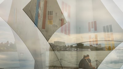 Doppelte Belichtung von Kunstinstallation und Stadtlandschaft am Flussufer.