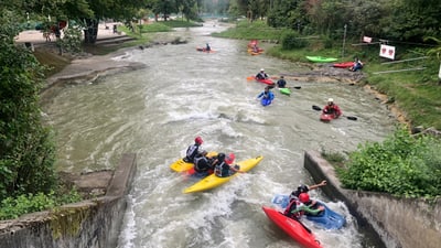Gruppe von Kajakfahrern auf einem Fluss bei Wildwasserfahrt.