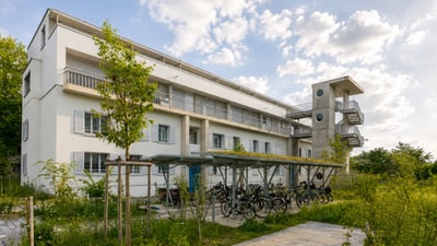 Weies Wohngebäude mit Fahrradabstellplatz und B�umen.