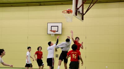 Jugendliche spielen Basketball in der Turnhalle.