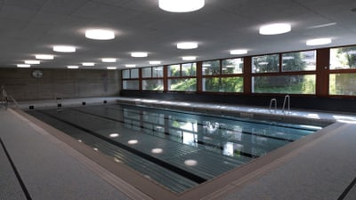 Hallenbad mit grossen Fenstern und Beleuchtung.