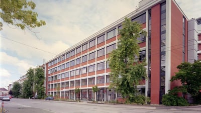 Fünfstöckiges rotes Backsteingebäude an einer Strasse.