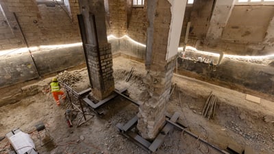 Bauarbeiter in einem alten Gebäude mit freigelegten Strukturen.