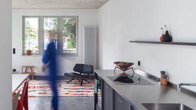 Moderne Küche mit Person in Bewegung und farbigem Teppich.