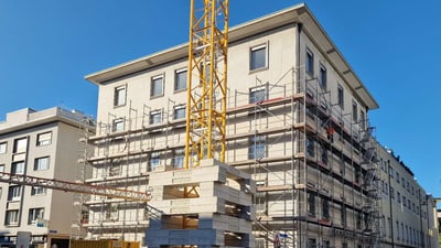 Gebäude mit Baugerüst und grossem Kran davor.