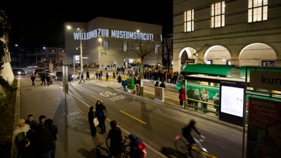 Menschen vor einem Museum bei Nacht.