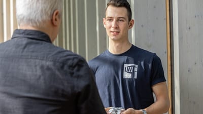 Junger Mann spricht mit älterem Mann im Freien.