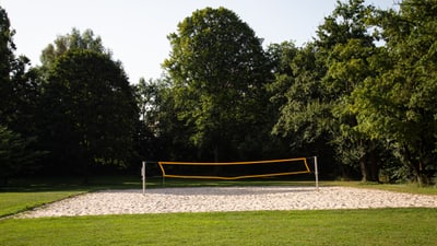 Sand-Volleyballplatz im Park mit Bäumen im Hintergrund.