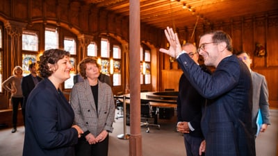 Menschen in einem holzgetäfelten Raum, in Gespräch vertieft.",