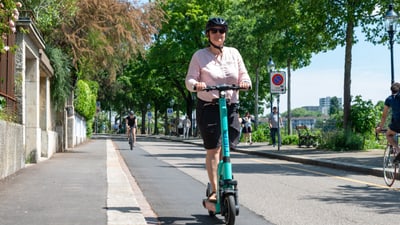 Person fährt E-Trotinett am Rheinbord in Basel.