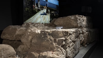 Römische Umfassungsmauer im Vordergrund, Rekonstruktionszeichnung der Mauer im Hintergrund.