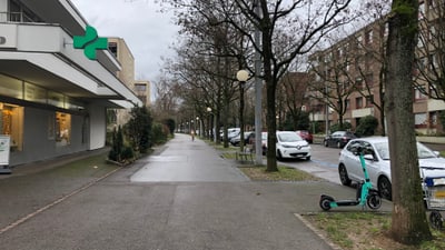 Stadtstrasse mit geparkten Autos und E-Scooter.",