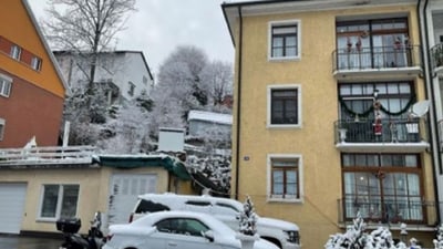 Wohngegend im Winter mit Schnee auf Autos und Gebäuden.