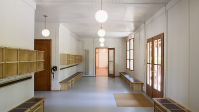 Heller Umkleideraum mit Holzbänken und Schliessfächern.