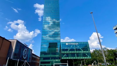Glasgebäude Hyperion unter blauem Himmel.