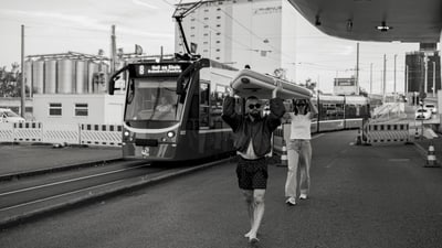 Siegerbild vom Fotowettbewerb, wobei zwei Personen mit Surfbrett über die schweizerisch-deutschen Grenze laufen.