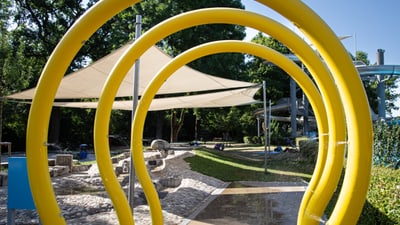 Spielplatz mit gelben Wasserbögen und Sonnensegel.