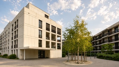 Modernes Gebäude mit Bäumen im Innenhof bei sonnigem Wetter.