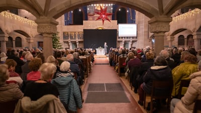 Eine Präsentation in einer Kirche vor einer sitzenden Menschenmenge.