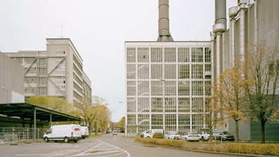 Industriegebäude mit geparkten Autos im Vordergrund.