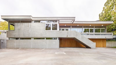 Modernes Betongebäude mit grossen Fenstern und Treppe aussen.