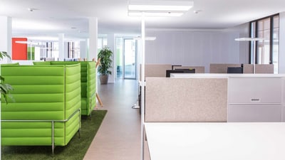 Modernes Bürointerieur mit grünen Sofas und weissen Schreibtischen.