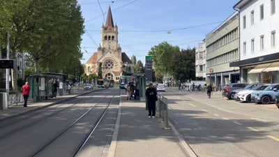 Stadtstrasse mit Strassenbahnschienen, Kirche im Hintergrund.