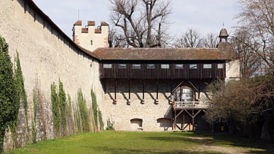 Alte  hohe Stadtmauer mit Holzaufbau und Türmen.