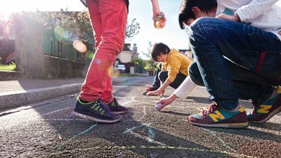 Kinder malen mit Kreide auf der Strasse.