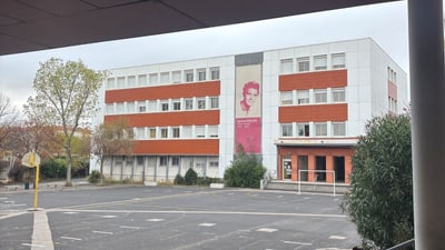 Schulgebäude mit Basketballplatz davor.