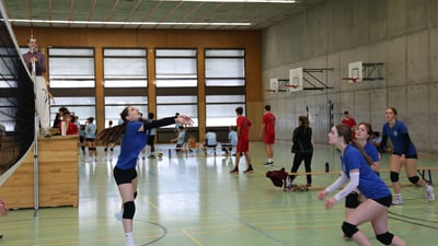 Frauen-Volleyballspiel in einer Turnhalle.