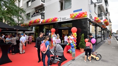 Feier vor einem Gebäude mit rotem Teppich und Luftballons.