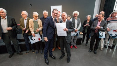Gruppe von Menschen bei einer Preisverleihung, zwei Männer halten eine Urkunde.