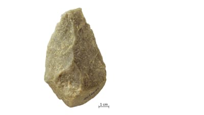Einzelner grauer Stein auf weissem Hintergrund.