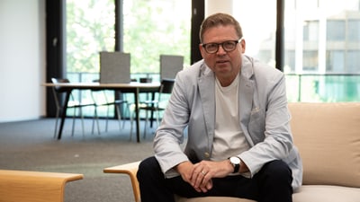 Roger Kemmler sitzt auf Sofa in modernem Büro.