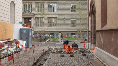 Arbeiter pflastern eine Kopfsteinpflaster-Strasse in einer Stadt.